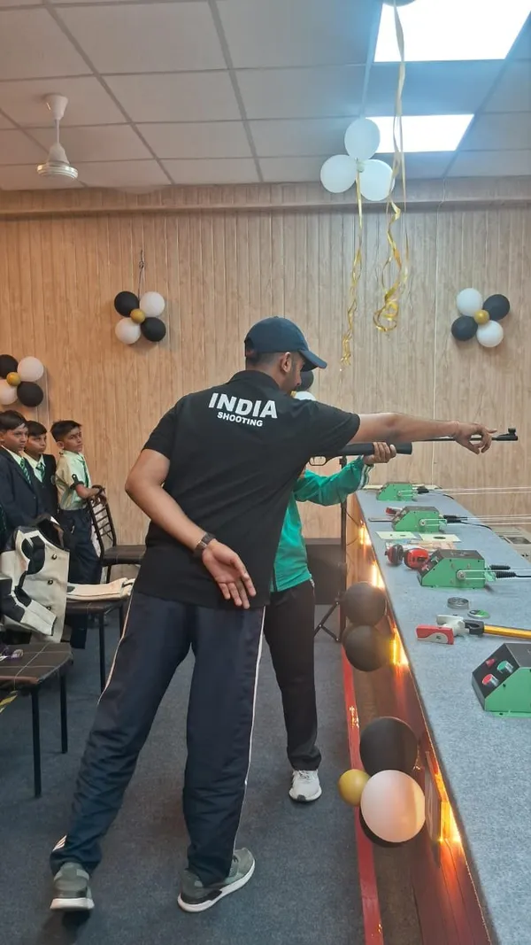 A coach demonstrating the pistol stance to a student at the shooting range