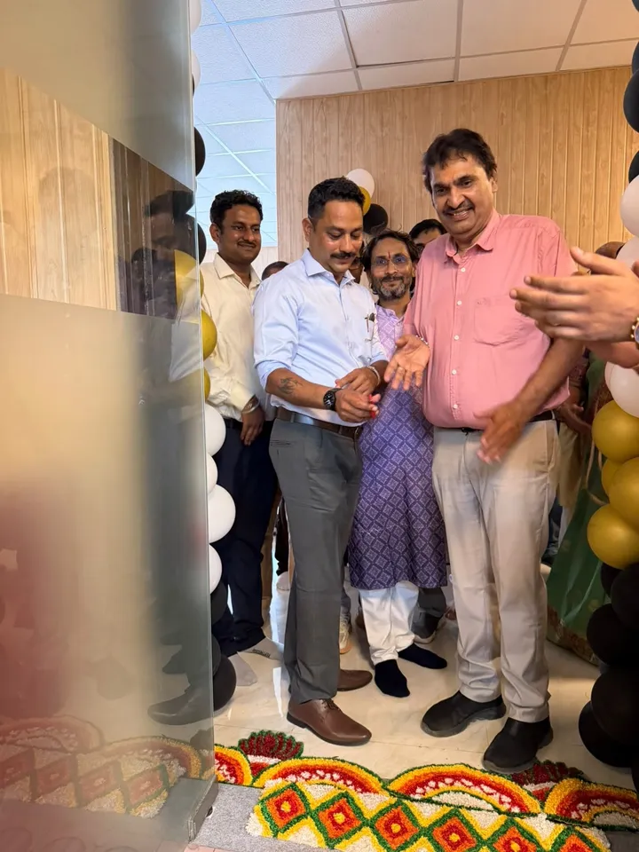 Guests greeting each other near a rangoli and balloon decorations at the academy opening