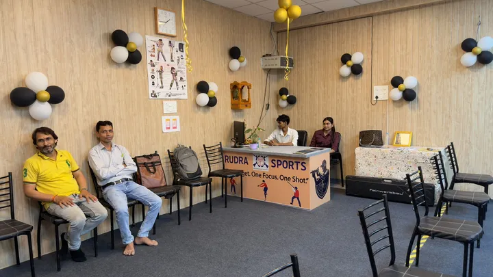 Visitors seated near the Rudra Sports reception desk inside the range hall
