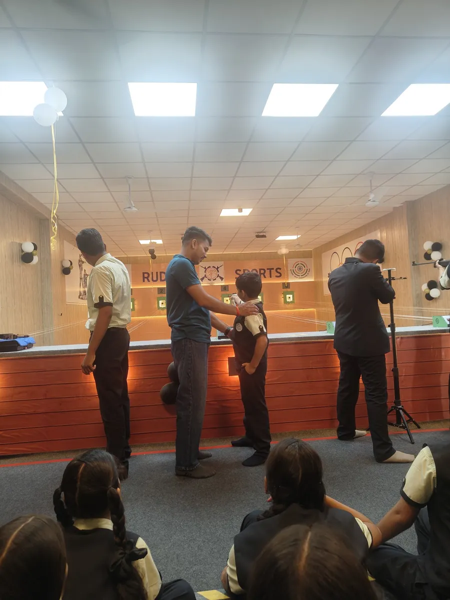 A coach adjusting a young student's position while other students watch