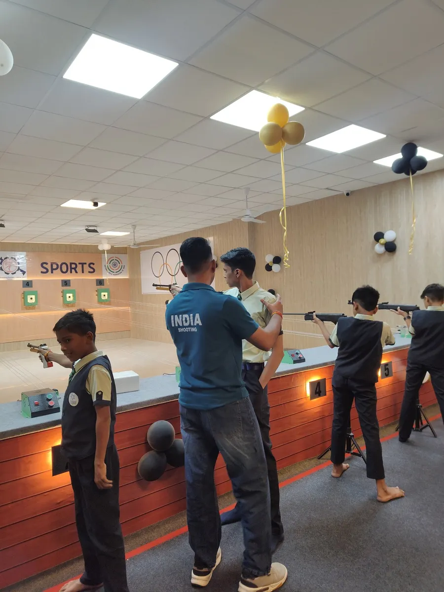 Young students taking aim with air pistols at the firing line with a coach beside them