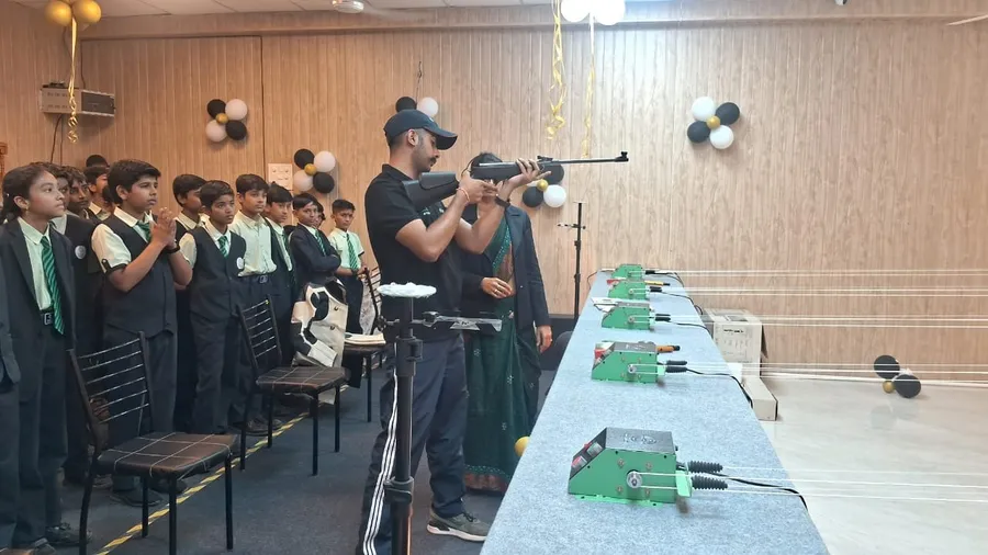 A coach demonstrating how to aim an air rifle while students in uniform watch